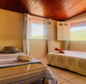 a bedroom with two beds and two windows at Vila das Estrelas - Guesthouse in Lençóis