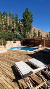 a couple of lounge chairs on a deck with a pool at Milodge Elqui Domos in Pisco Elqui