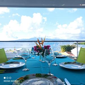 a table with wine glasses and a view of the water at Appartement Ti Bato in Les Trois-Îlets