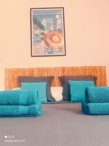 a bed with blue pillows and a picture on the wall at Appartement Ti Bato in Les Trois-Îlets