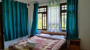 a bedroom with blue curtains and a bed with two windows at Hotel Himsagar in Pemayangtse