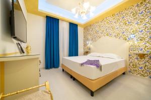 サレルノにあるLeucosya Luxury Roomsのベッドルーム(青いカーテン、テレビ付)