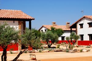 a house with red and white walls and trees at Finca El Encinar in Pedro Muñoz