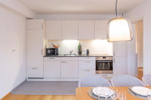 one bedroom apartment in trendy Zurich West في زيورخ: مطبخ مع دواليب بيضاء وطاولة مع كراسي