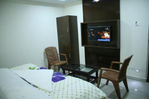 a living room with a couch and chairs and a tv at KVP Inn in Tirupati