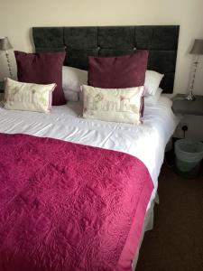 a large bed with purple and white sheets and pillows at The Coach and Horses in Parkham