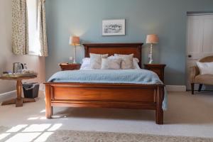 Un dormitorio con una gran cama de madera con almohadas en The Penrallt Country House Hotel, en Aberporth