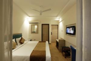 a bedroom with a bed and a flat screen tv at Le Seasons Resort in Candolim