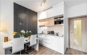 a kitchen with white cabinets and a table with chairs at Apartement Blanc de luxe in Prague