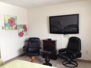 Zimmer mit 2 Stühlen und einem Flachbild-TV in der Unterkunft Chaparral Inn in Arcola