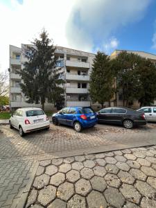 trzy samochody zaparkowane na parkingu przed budynkiem w obiekcie LoftMe Houses Hostel w Warszawie