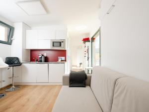 a white living room with a couch and a kitchen at Ipsmiller Appartements in Schrattenberg