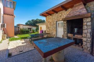a patio with a table and a stone fireplace at Apartments Davor in Banjole
