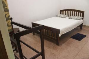 Holiday Home Anuradapura في أنورادابورا: سرير صغير في غرفة ذات اطار خشبي
