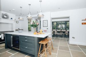 a kitchen with a blue island with a white counter top at Woodvale - Sleeps 20 in Harpsden