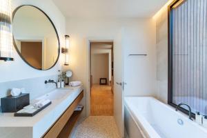 a bathroom with a large tub and a large mirror at Kimpton Aysla Mallorca by IHG in Santa Ponsa