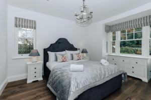 um quarto com uma cama grande e 2 janelas em Woodvale - Sleeps 20 em Harpsden