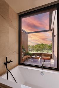 eine Badewanne im Bad mit einem großen Fenster in der Unterkunft Kimpton Aysla Mallorca, an IHG Hotel in Santa Ponsa