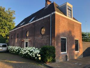 un edificio de ladrillo con un reloj a un lado en Koetshuis aan het water 3 bedroom villa en Voorburg