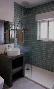 La salle de bains est pourvue d'un lavabo et d'un mur en carrelage vert. dans l'établissement Refúgio do Almograve, à Almograve