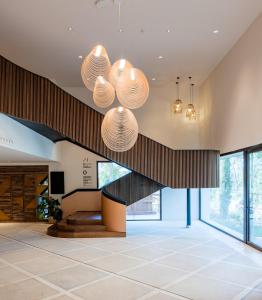 a lobby with a staircase and two chandeliers at Kimpton Aysla Mallorca by IHG in Santa Ponsa