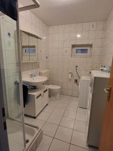 ein weißes Bad mit einem Waschbecken und einem WC in der Unterkunft Ferienwohnung Meisbüsch in Merzig