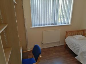um quarto com uma cama e uma cadeira azul e uma janela em Large House with 3 Bedrooms house, 5 guests near city/Manu stadiums em Manchester