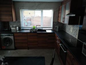 a kitchen with a sink and a washing machine at Large House with 3 Bedrooms house, 5 guests near city/Manu stadiums in Manchester