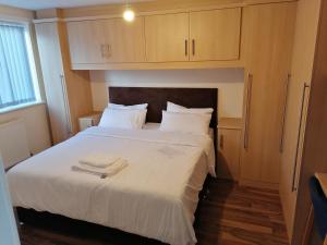 um quarto com uma cama grande com lençóis brancos e almofadas em Large House with 3 Bedrooms house, 5 guests near city/Manu stadiums em Manchester