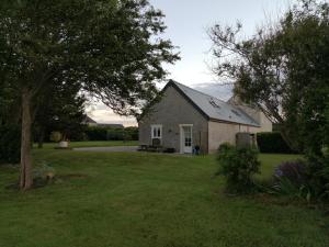 een huis in een tuin met een boom en gras bij Ivy House Utah Beach in Sainte-Marie-du-Mont