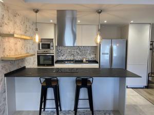 a kitchen with a black counter and two bar stools at GRAN COLL BLANC Confort in Pas de la Casa