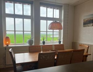 ein Esszimmer mit Tisch und Stühlen und Fenstern in der Unterkunft Landzicht Vakantiehuis aan de Fluessen in Elahuizen + 14 Fotos