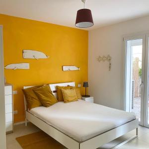 a bedroom with a bed with a yellow wall at Lupicante 56 Cesenatico in Cesenatico