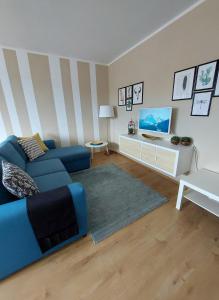 ein Wohnzimmer mit einem blauen Sofa und einem TV in der Unterkunft Apartment Graz Murpromenade in Graz
