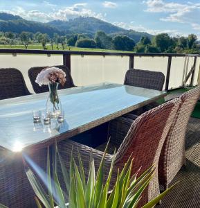 einen Tisch mit Stühlen und eine Vase mit Blumen auf einer Terrasse in der Unterkunft Ferienhaus Auenblick DELUXE in Eisenach