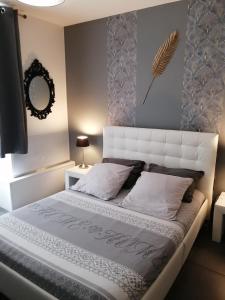 - une chambre avec un grand lit et une tête de lit blanche dans l'établissement Ô Temps d'Amour Sauna&Jacuzzi, à Malissard