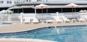 a swimming pool with chairs and umbrellas and a building at The Inn Of Cape May in Cape May