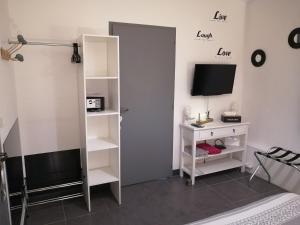 een kamer met een bed, een televisie en een bureau bij Ô Temps d'Amour Sauna&Jacuzzi in Malissard
