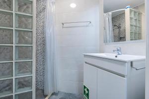 Baño blanco con lavabo y espejo en Chale Bela, en Setúbal