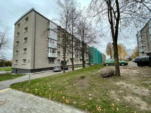 un edificio al lado de una calle con un árbol en Jaukūs apartamentai miesto centre en Šiauliai
