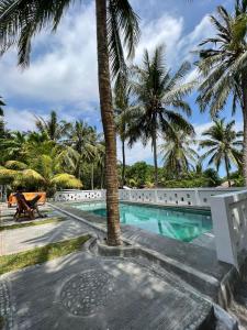 a resort swimming pool with palm trees in the background at Kuta Circle Homestay in Kuta Lombok