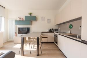 a kitchen with white cabinets and a table at We Home - Santa Sofia House, Duomo in Milan
