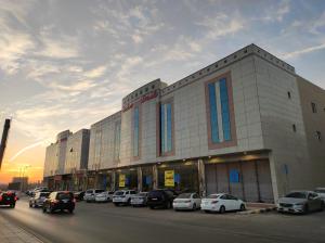 a large building with cars parked in a parking lot at Brzeen Hotel Riyadh in Riyadh