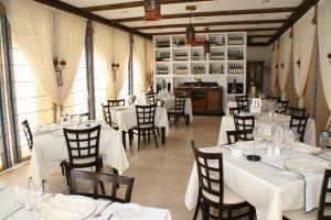 a dining room with white tables and chairs and windows at Finca El Encinar in Pedro Muñoz