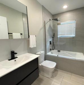 a bathroom with a sink and a toilet and a tub at Hillsboro Suites & Residences Condo Hotel, St Kitts in Basse Terre Town