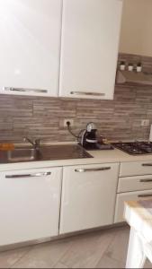 eine Küche mit weißen Schränken und einem Waschbecken in der Unterkunft LONATE SUITE in Lonate Ceppino