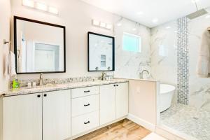a white bathroom with two sinks and a tub at Sea Flamingo in Cape Canaveral +25 photos