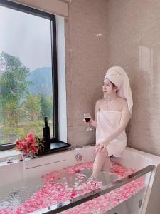 a woman sitting in a bath tub with a glass of wine at Trang An Resort in Ninh Binh