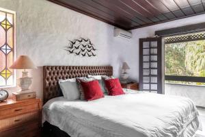 Sítio com lazer completo e natureza em Guararema في جاكاري: غرفة نوم بسرير كبير ومخدات حمراء