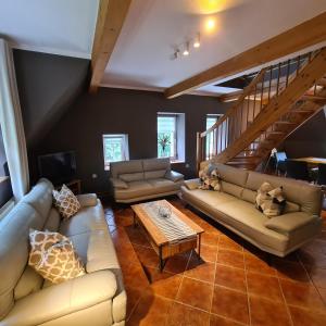 ein Wohnzimmer mit Sofas und einer Treppe in der Unterkunft Appartements im "Landhaus am Frohnauer Hammer" in Annaberg-Buchholz